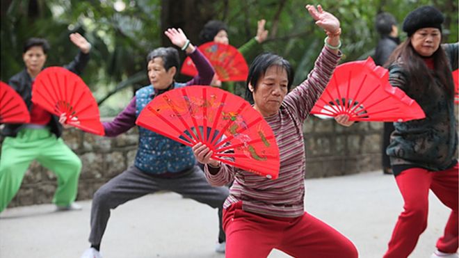 group preforming Tai Chi with fans
